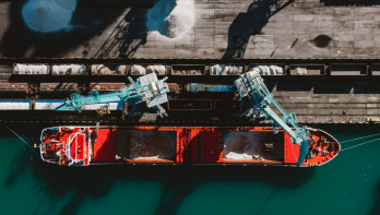 Kunstmest die in een vrachtschip wordt geladen voor transport over water.