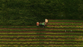 Luchtfoto van een tractor die gras maait op landbouwgrond
