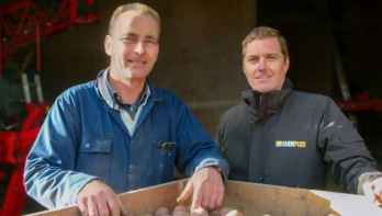 Dwóch mężczyzn pozuje obok skrzynki z ziemniakami