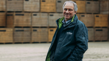 Guus Bergmans poseert lachend voor stapels met kratten