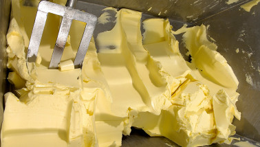 Productie van boter in een zuivelfabriek, verse boter gevormd tijdens industriële verwerking van room