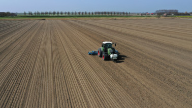 Trekker met zaaimachine zaait uien op akkerbouwgrond
