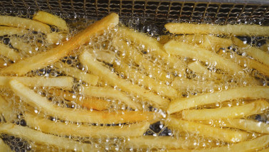 Frites bakken in hete olie, bereiding van knapperige aardappelfriet