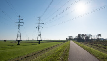 Elektriciteitsmasten op grasland in een open landschap.