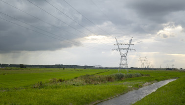 Elektriciteitsmasten op grasland in een open landschap.