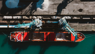 Kunstmest die in een vrachtschip wordt geladen voor transport over water.