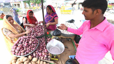 Indiase vrouw die rode uien koopt bij een groenteverkoper op een lokale markt in India.