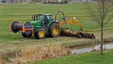 Tractor met een Tjalma-sleepslang zodebemester die drijfmest emissiearm in een grasland injecteert.