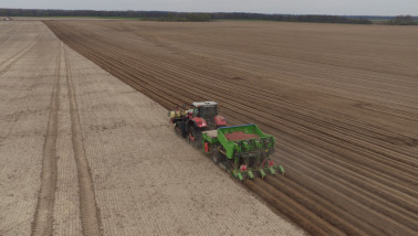 Trekker plant pootaardappelen op een groot akkerbouwperceel,