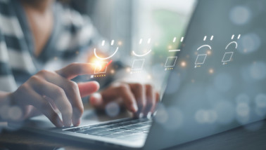 Persoon geeft een online beoordeling door een glimlachend gezicht met vijf sterren aan te klikken op een laptop