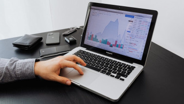 Hand op laptop met financiële grafieken op het scherm