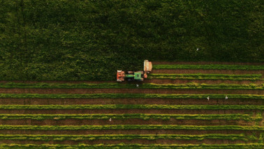Luchtfoto van een tractor die gras maait op landbouwgrond