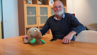Een man zit aan een tafel met een knuffel in de vorm van een aardappel
