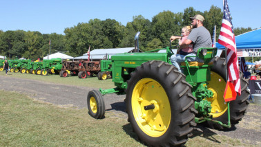Amerikaanse boer rijdt met John Deere vintage tractor.