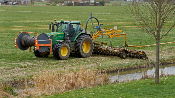 Tractor met een Tjalma-sleepslang zodebemester die drijfmest emissiearm in een grasland injecteert.
