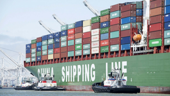 OAKLAND, CA – 3 mei 2015: het vrachtschip CSCL Spring van China Shipping Lines vaart de haven van Oakland binnen, waarbij meerdere sleepboten het schip assisteren bij het manoeuvreren.