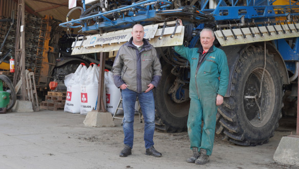 Twee mannen staan bij een grote zelfrijdende veldspuit in een landbouwschuur