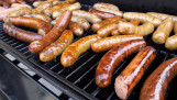 Worstjes op de barbecue die worden gegrild.