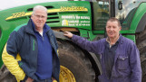 Twee mannen poseren bij een John Deere trekker