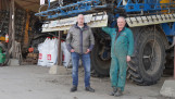 Twee mannen staan bij een grote zelfrijdende veldspuit in een landbouwschuur
