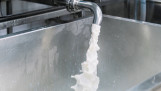 Melk gieten uit een kraan in een vat tijdens de verwerking in een moderne zuivelfabriek
